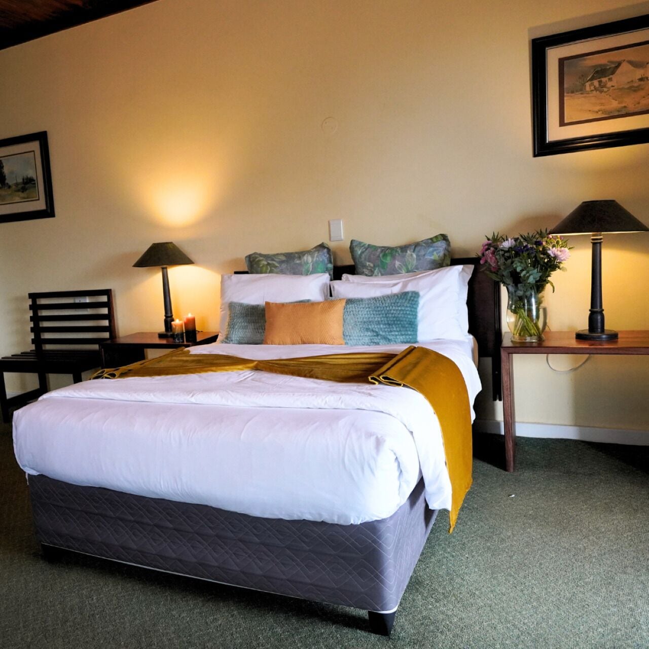 Un lit bien fait, avec un matelas matelassé, une table de chevet avec une lampe et un vase de fleurs posé sur la table de chevet.