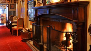 A cozy room with a fireplace, wooden ceiling, and a red carpet.