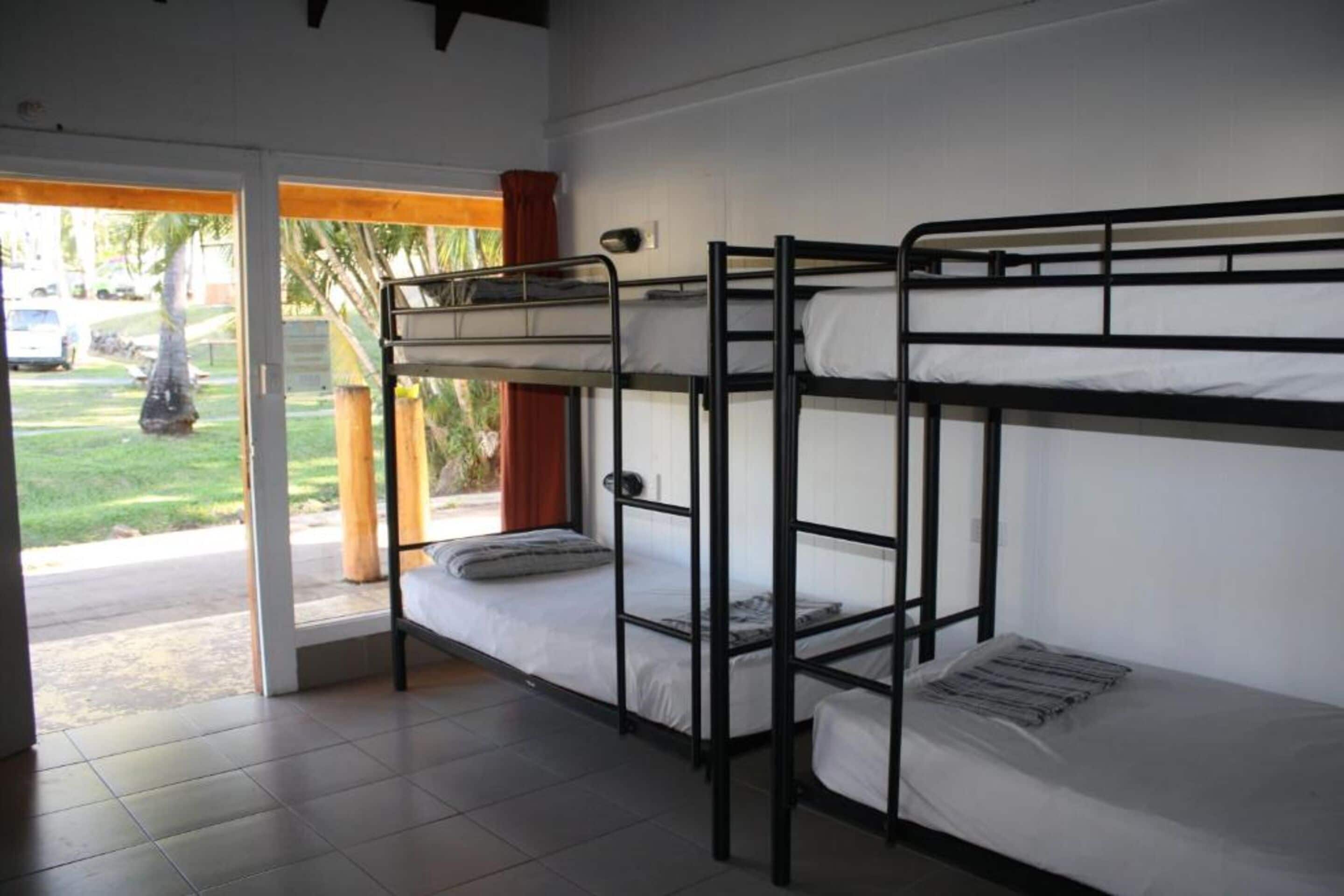 Un dormitorio con literas, una ventana con vistas al exterior y una puerta que da al exterior.