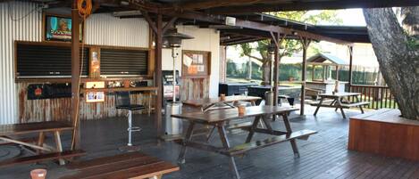 An outdoor patio area with wooden picnic tables and a barbecue station.
