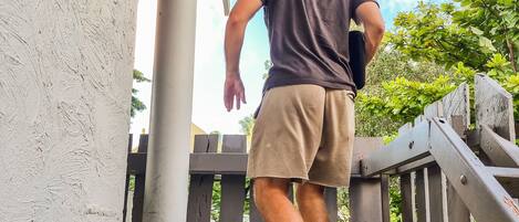 A person descending a concrete staircase with a metal railing, under a corrugated metal roof.