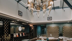 A spacious lobby with a high ceiling, a modern chandelier, plush seating, and a large mirror. - La Prima Fashion Hotel (Budapest)