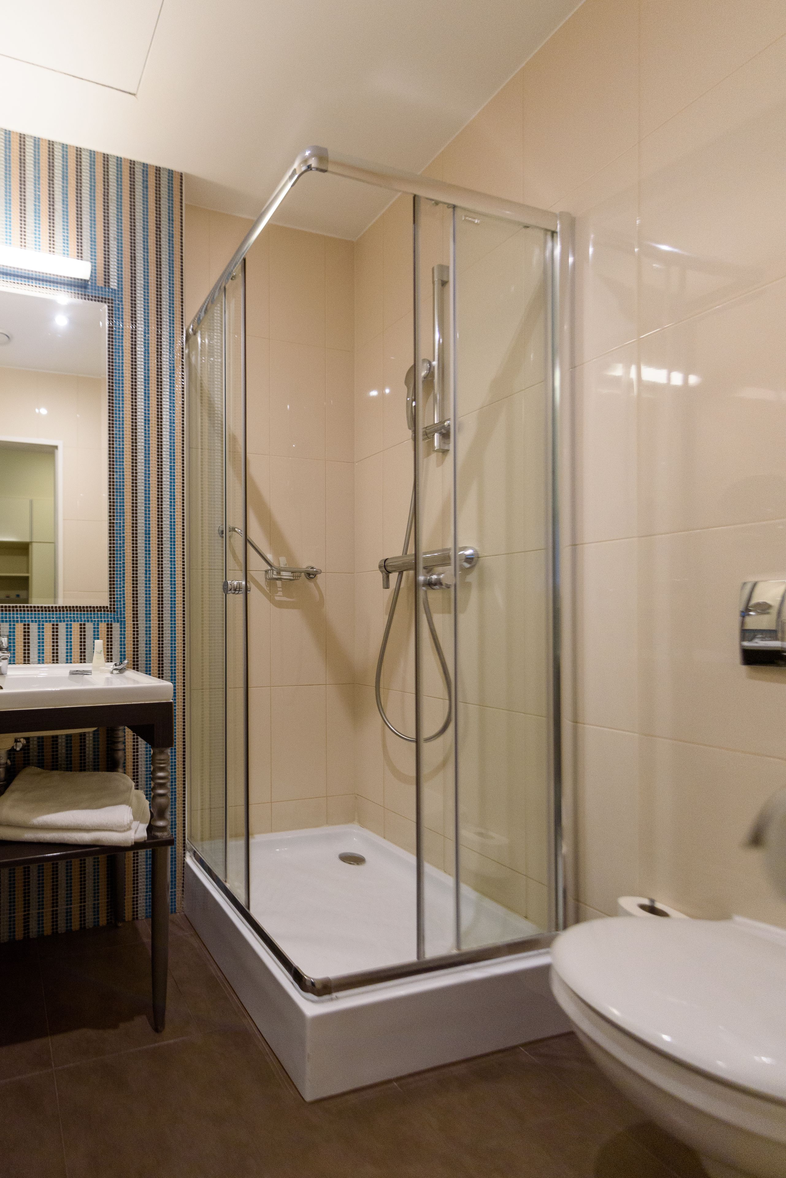 A modern bathroom with a glass-enclosed shower, a white toilet, and a sink with a mirror above it.
