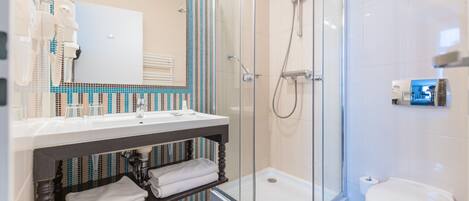 Un baño moderno con ducha acristalada, lavabo blanco y retrete.