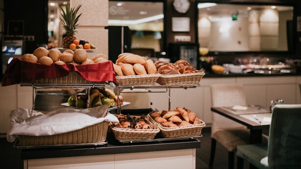 A buffet counter with various breads, pastries, and fruits. - La Prima Fashion Hotel (Budapest)