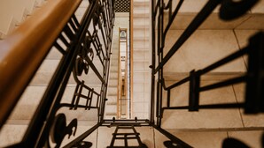 A view down a stairwell with metal railings and a wooden handrail. - La Prima Fashion Hotel (Budapest)