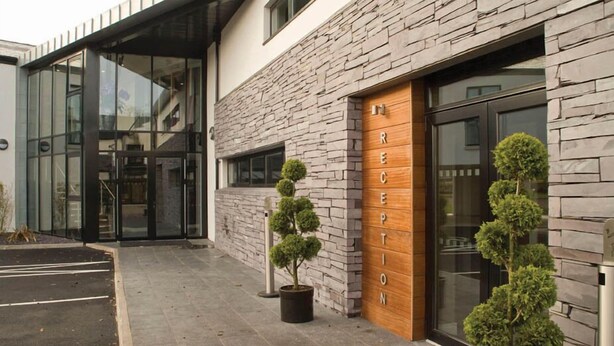 A modern building with a stone facade, a reception area with a wooden door, and a glass entrance.