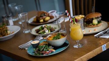 A dining table with various dishes, including a salad, a sandwich, and a glass of juice.