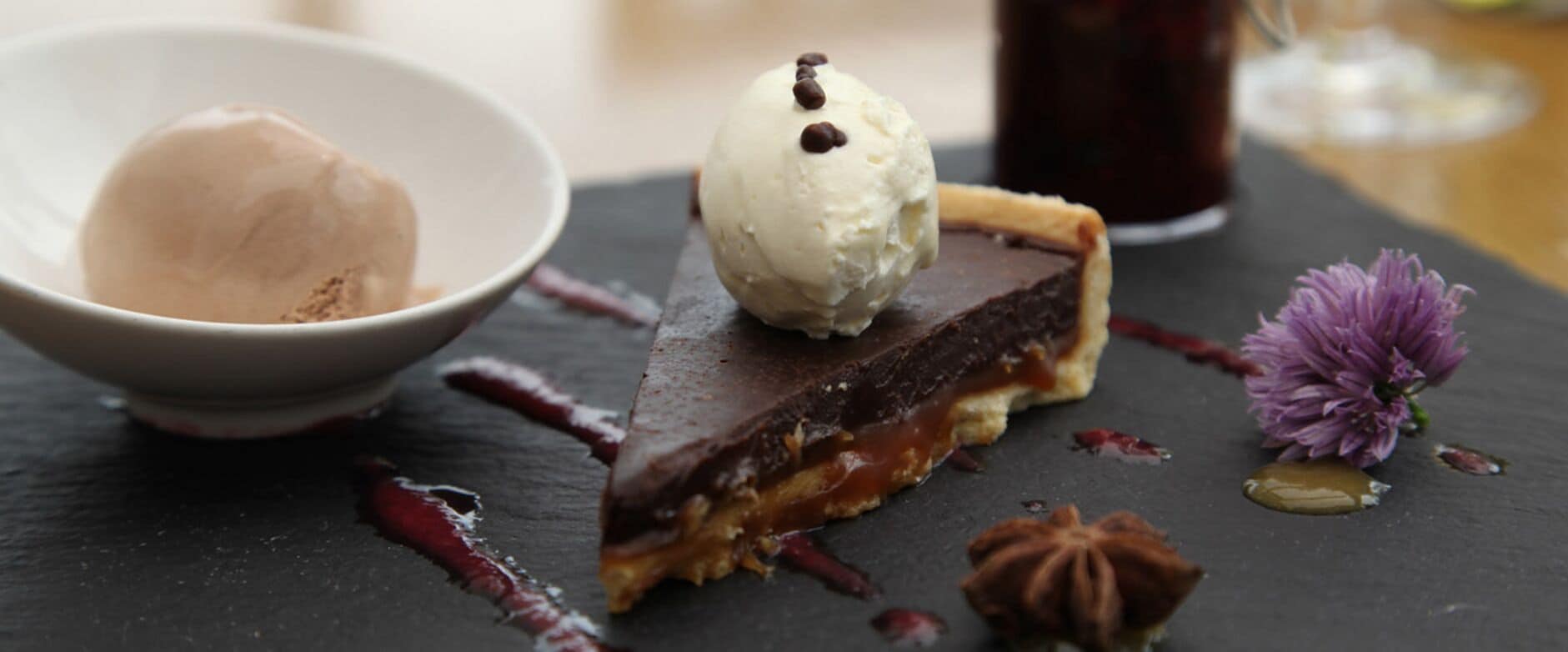 Un plato de postre con una porción de pastel y una bola de helado.