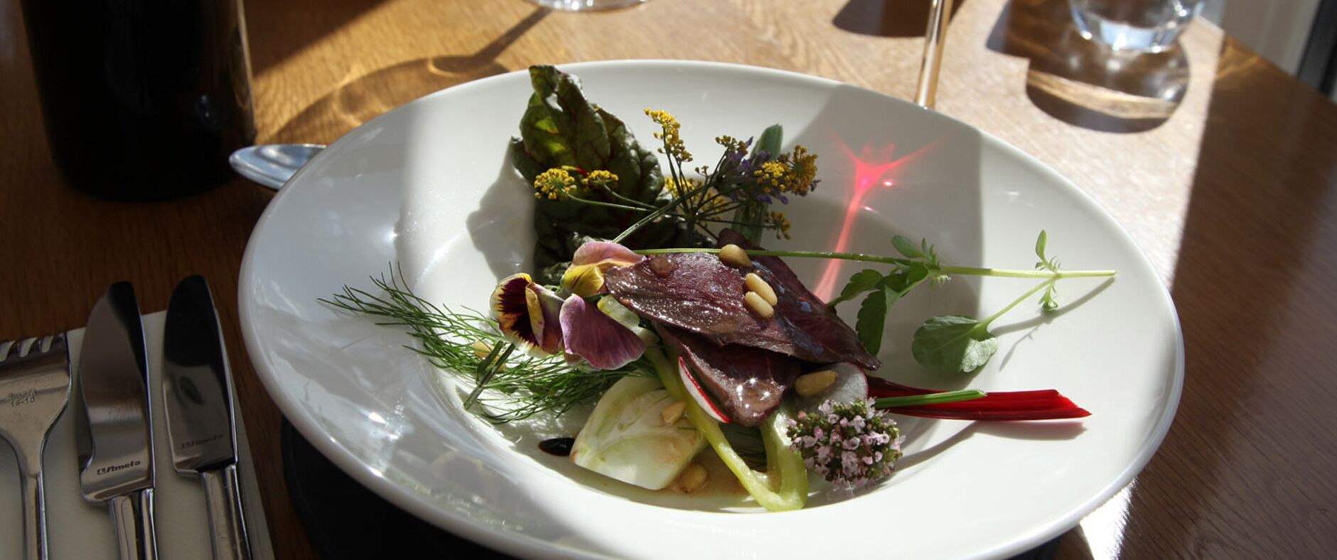 A white plate with a salad on a wooden table.