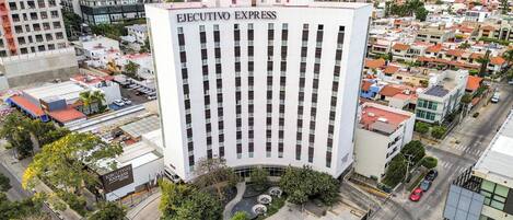 A high-rise building with 'EJECUTIVO EXPRESS HOTEL' signage, surrounded by urban buildings and a parking lot.