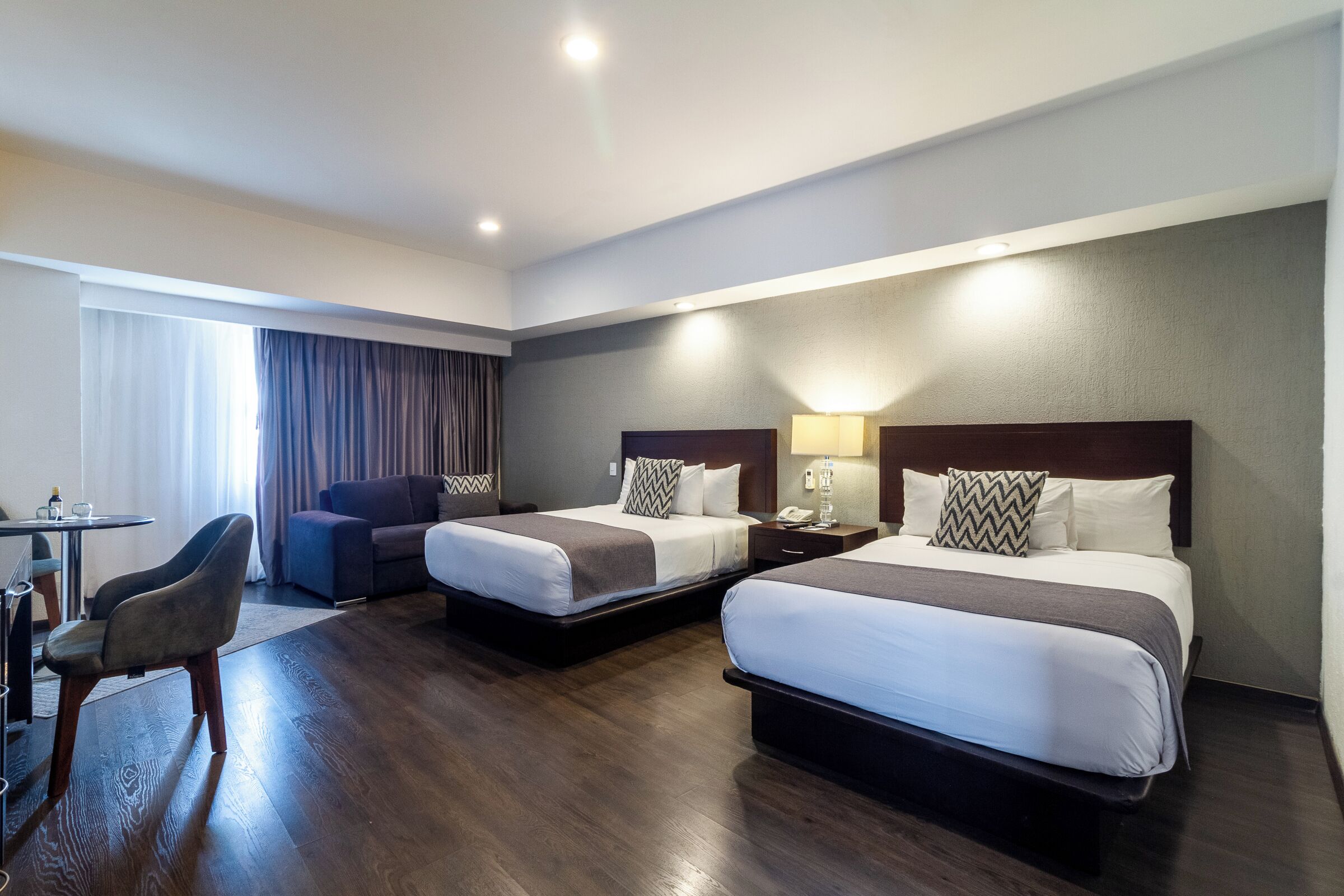Habitación de hotel con dos camas, un escritorio y una silla.