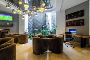 Un interior moderno con televisor, asientos, escritorio y vista a una pared de ladrillo y plantas.
