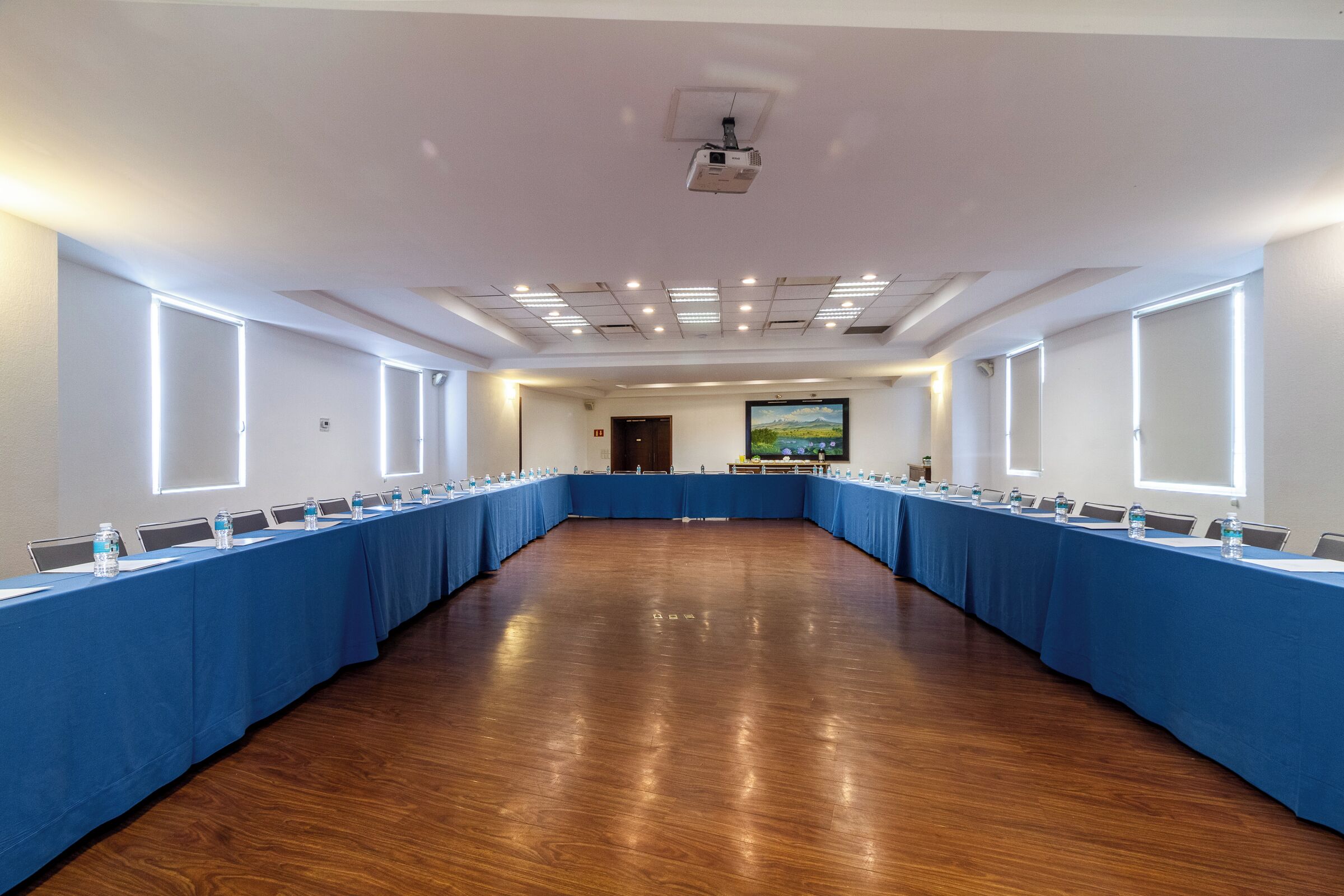 Een vergaderzaal met een lange tafel, stoelen en een projecteerder.