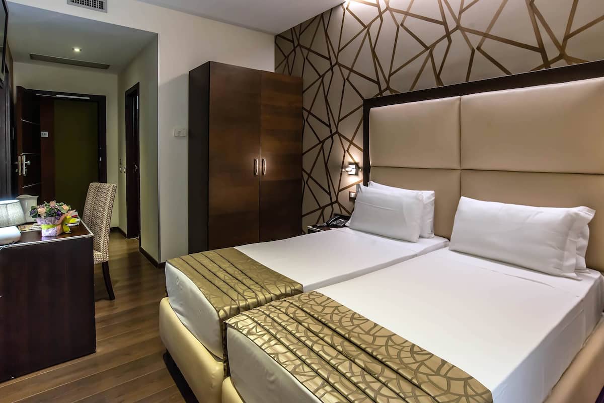 A hotel room with a large bed, a desk with a computer, and a wardrobe.