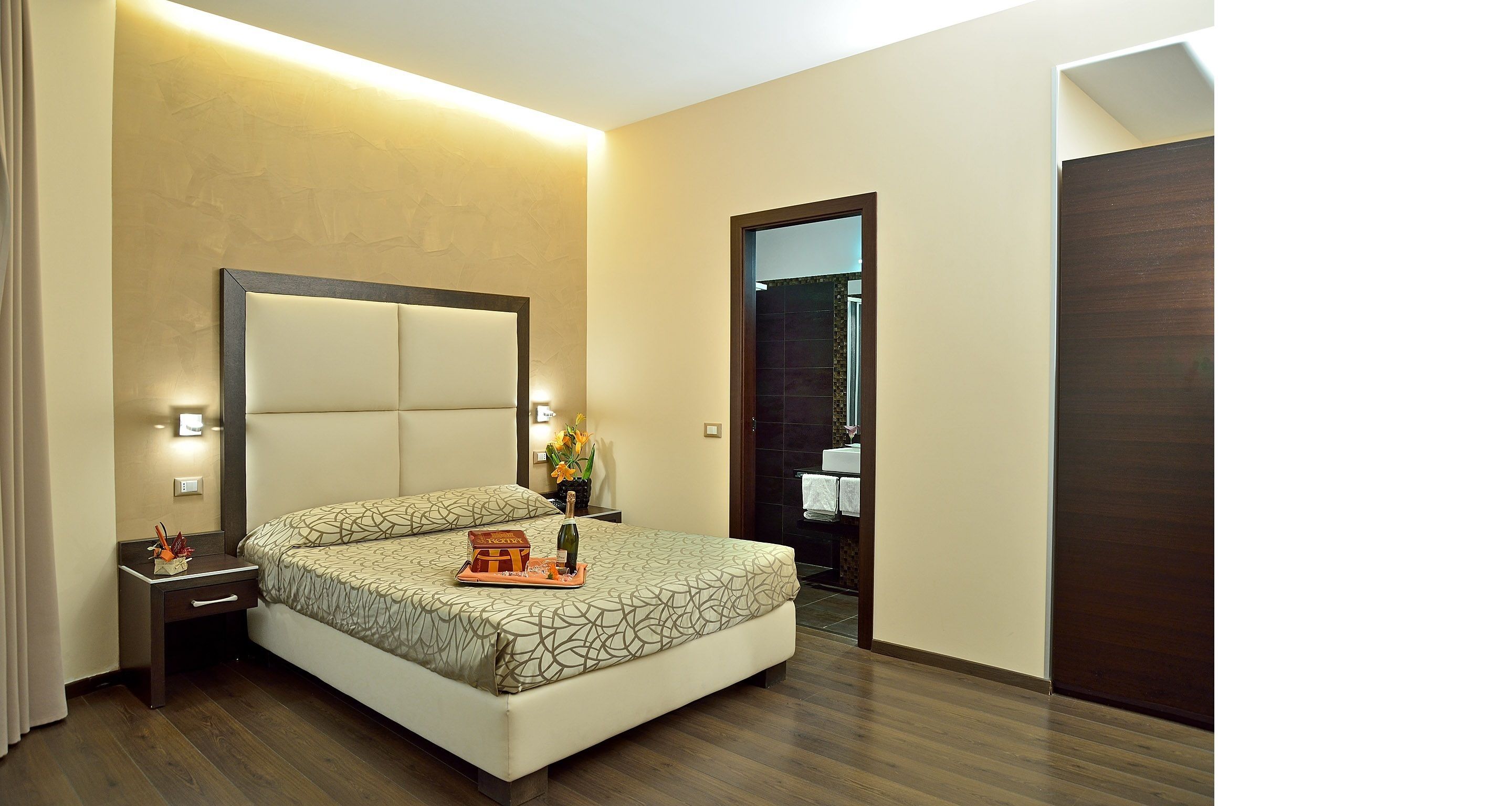Una habitación de hotel con cama, mesita de noche y espejo.