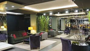 A modern lobby with sofas, armchairs, and a large potted plant.