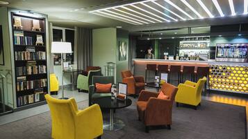 A modern lobby with a bar area, seating, and a bookshelf.