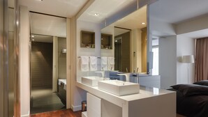 A modern bathroom with a large mirror, two sinks, and a walk-in shower.