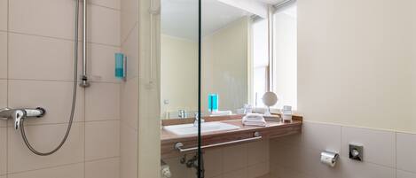 Une salle de bain moderne avec une douche à parois de verre, un meuble-lavabo en bois, un grand miroir et des toilettes.