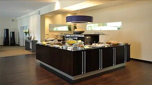 A modern kitchen with a central island, built-in appliances, and a large window. - Hotel am Schlosspark (Husum)