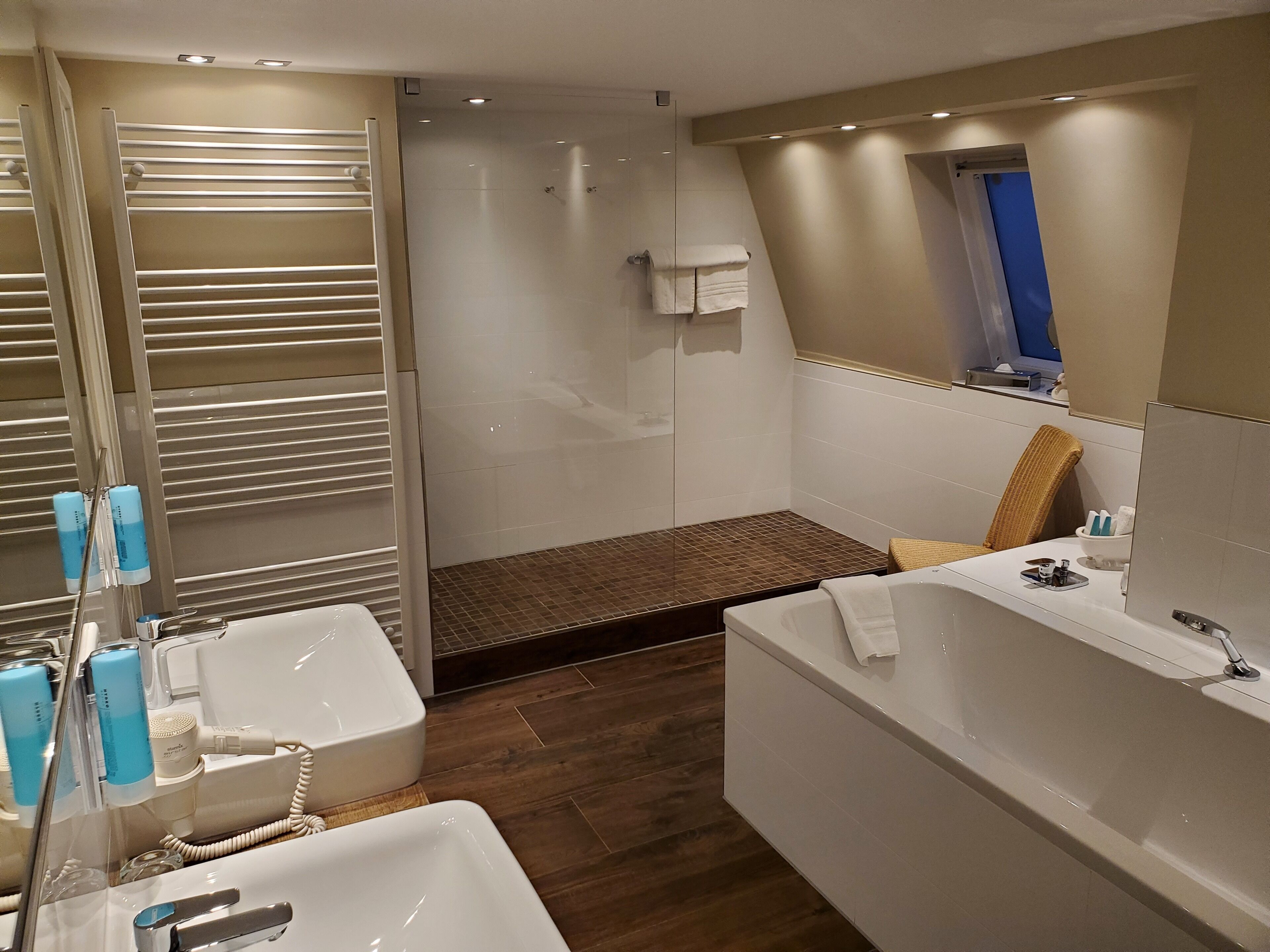 Un baño moderno con una bañera grande, zona de ducha separada y tocador con espejo.