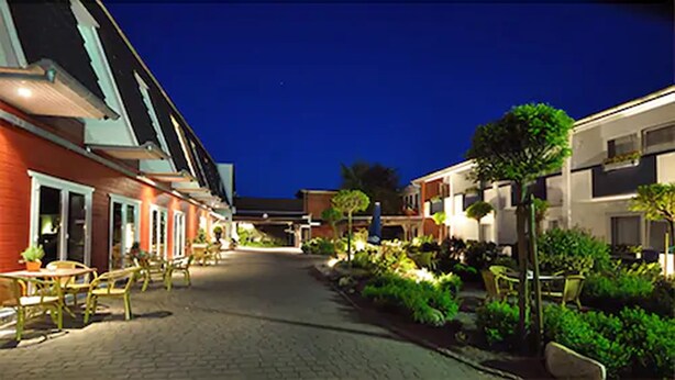 A hotel corridor with outdoor seating and greenery. - Hotel am Schlosspark (Husum)