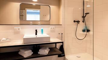 A modern bathroom with a glass-enclosed shower, a white sink, and a mirror above it.
