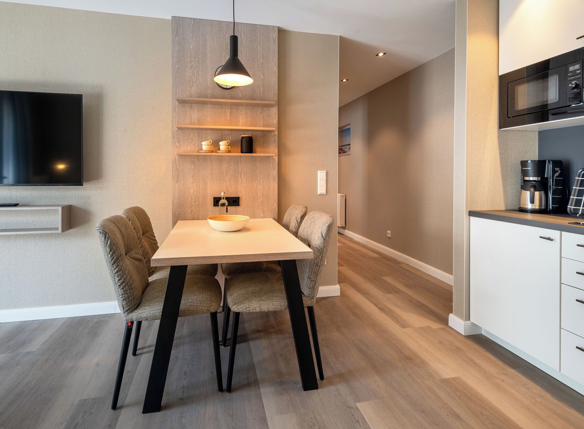 Une cuisine moderne avec une table à manger, des chaises et un téléviseur fixé au mur.