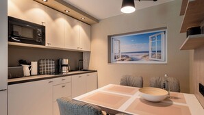 A compact kitchen with a microwave, coffee maker, and a window with a beach view. - Hotel am Schlosspark (Husum)