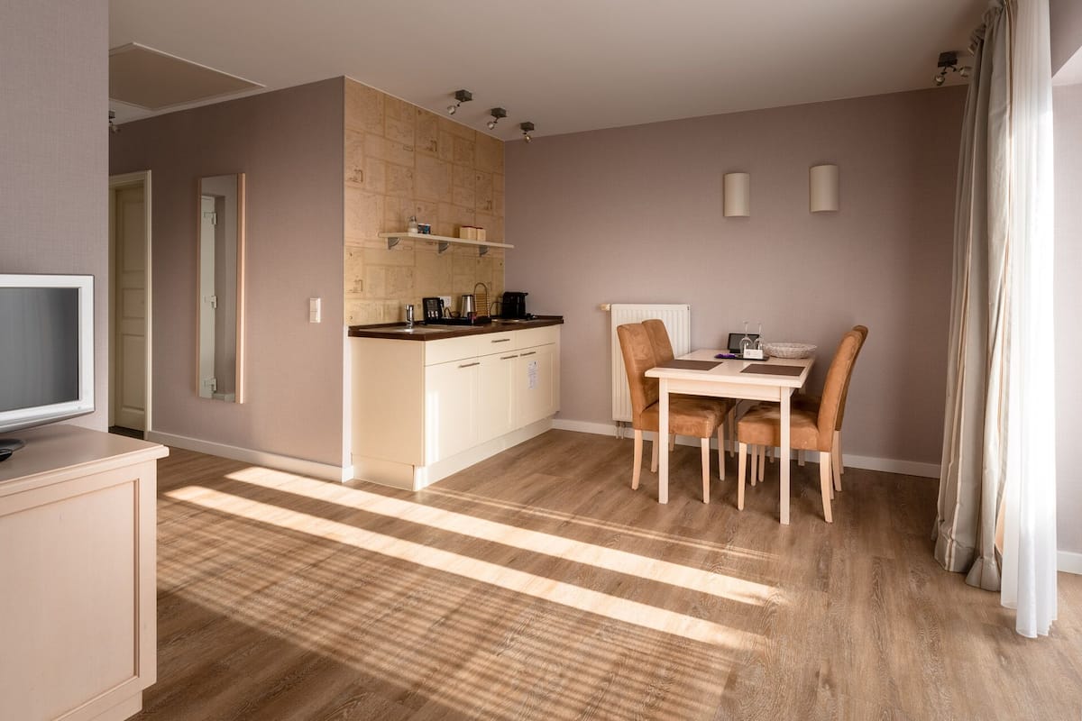 A compact living space with a kitchenette, a dining area with two chairs, a television, and a window with curtains.