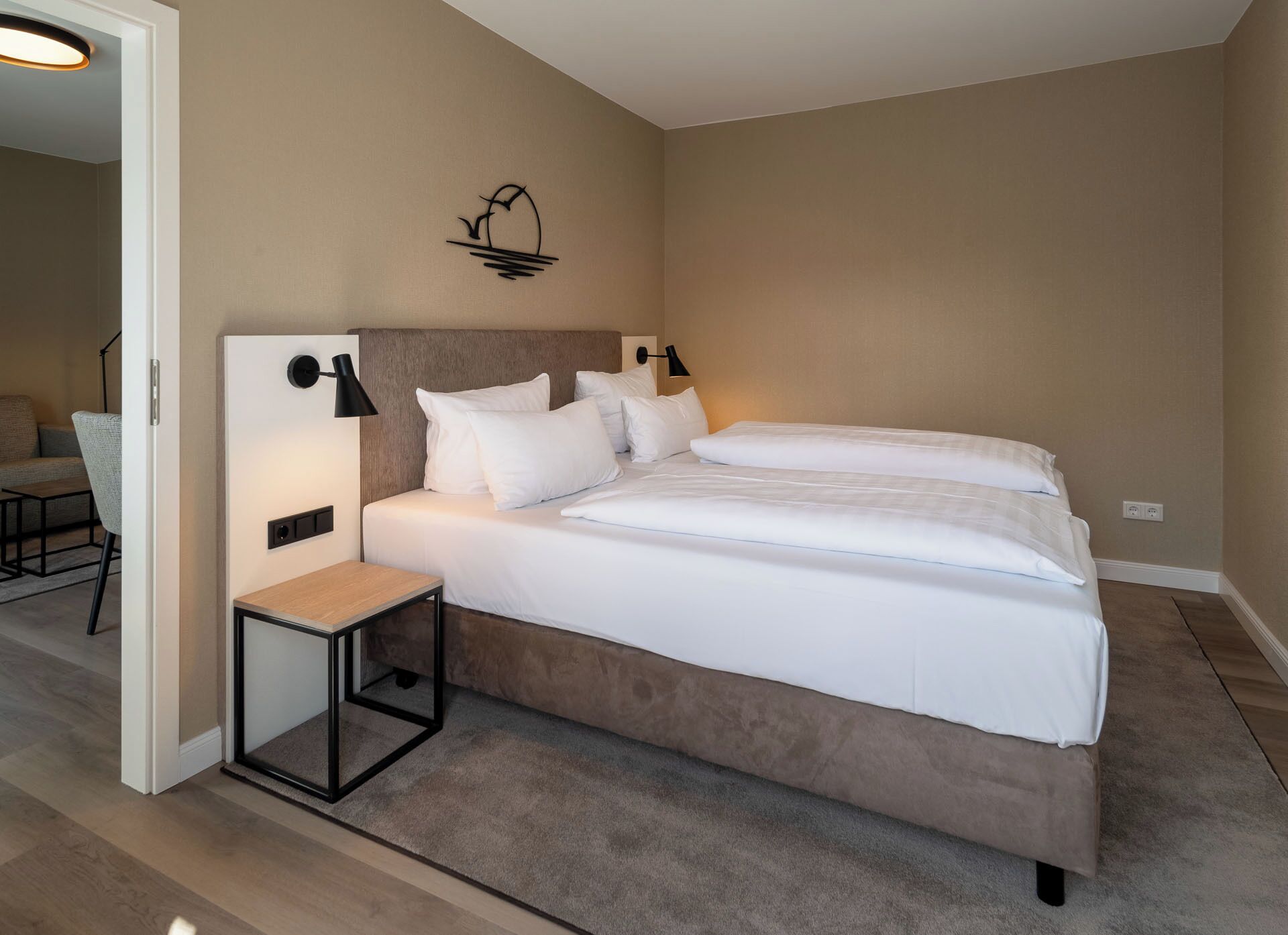 Una camera d'albergo moderna con un letto grande, comodini e una piccola scrivania.