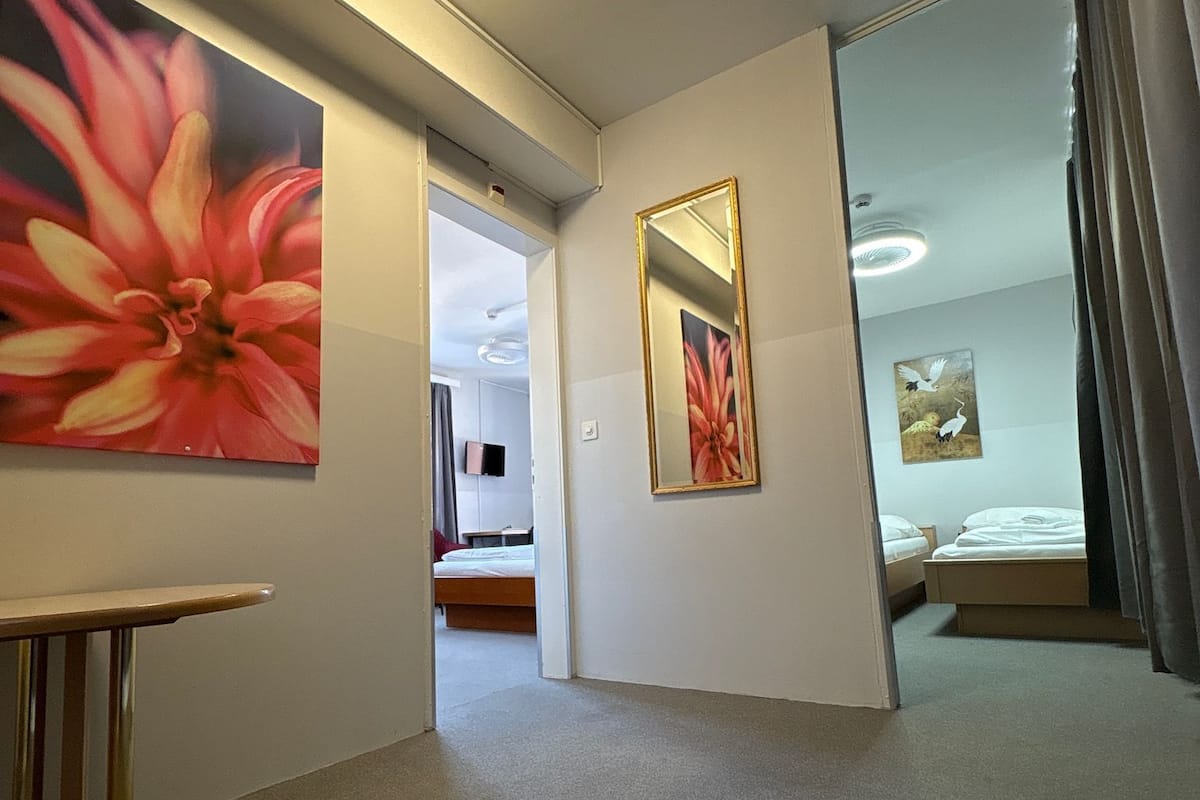 A hotel room with a large floral painting, a mirror, and a bed.