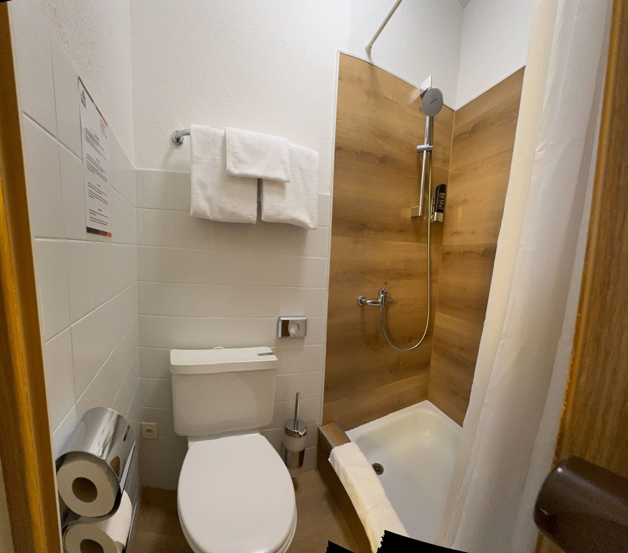 A small, modern bathroom with a toilet, sink, and shower.