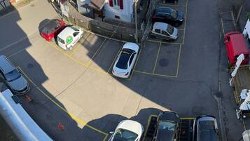 A parking lot with multiple cars and a building with red shutters.