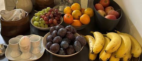 A table with various fruits, a pitcher, and some condiments.