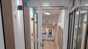 A modern hallway with wooden paneling, a potted plant, and a sign indicating a restroom.