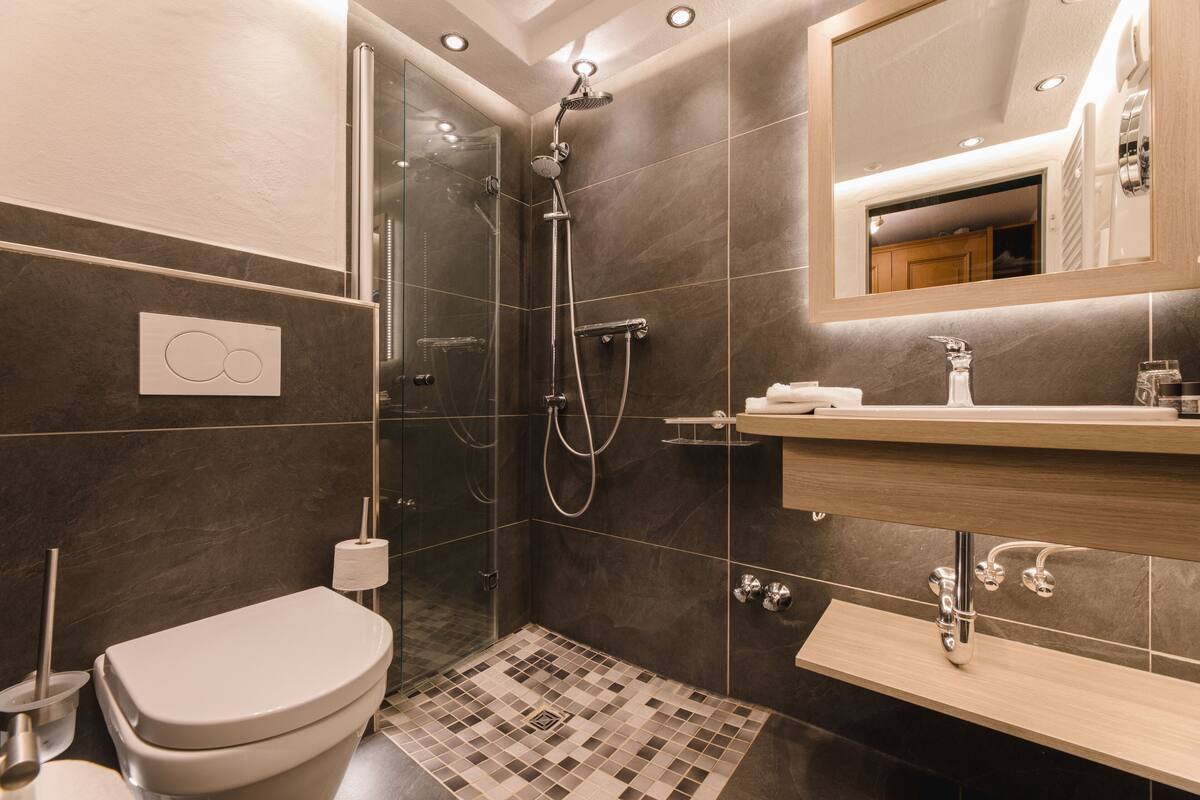 A modern bathroom with a glass-enclosed shower, a toilet, and a vanity with a mirror.