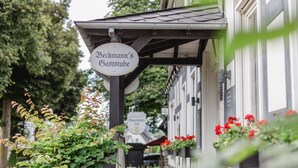 Un edificio con un letrero que dice "Beckmann's Gaststube" y macetas de flores en los alféizares de las ventanas.