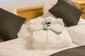Una cama bien hecha con una toalla blanca, una botella pequeña y un paño blanco.