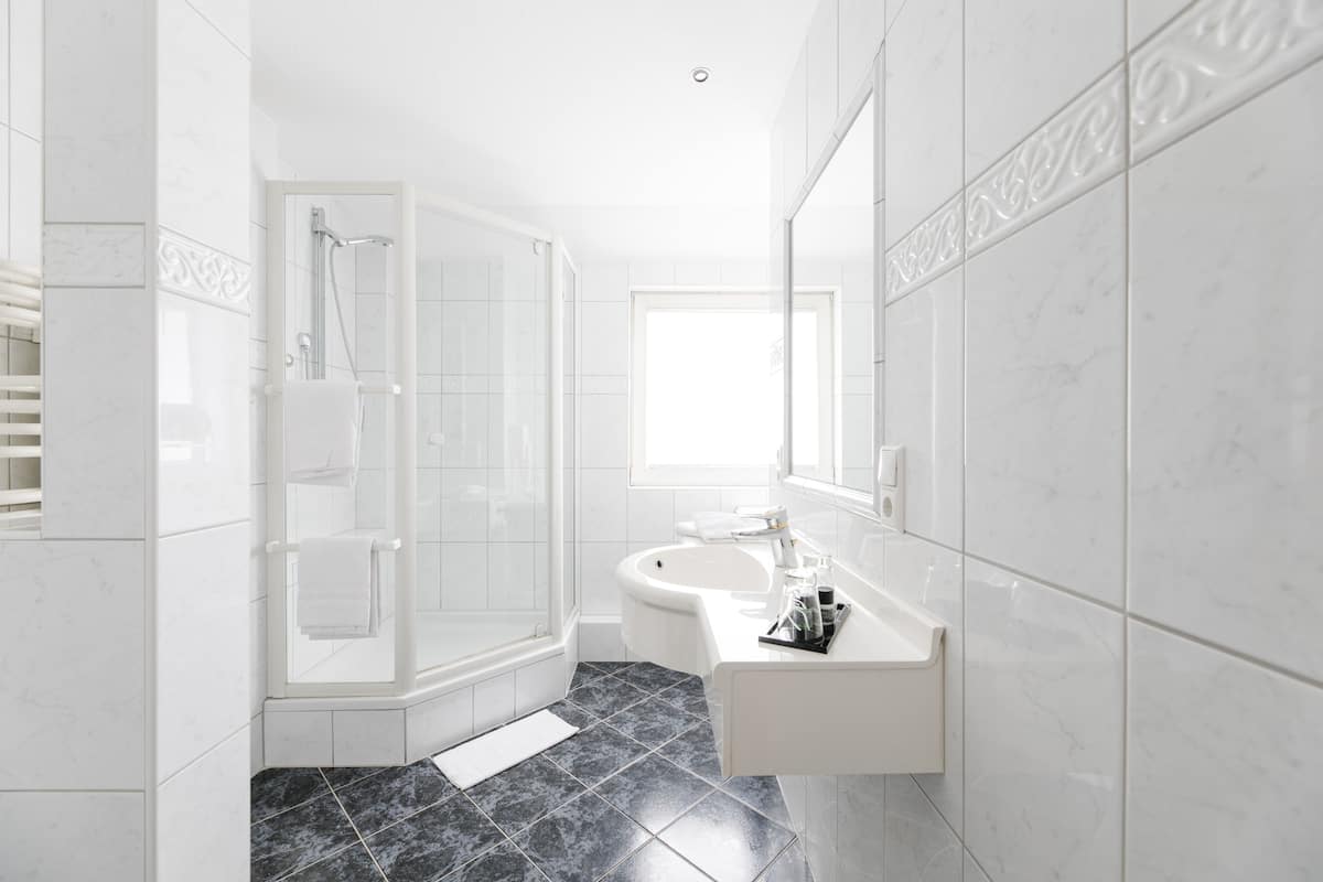 A modern bathroom with a glass shower enclosure, a white sink, and a large mirror.