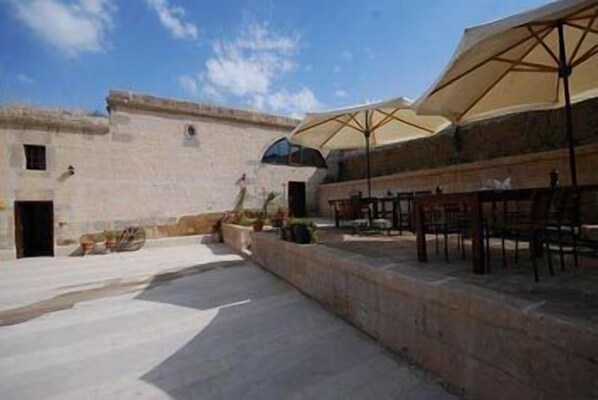 A courtyard with outdoor seating and a large umbrella. - Karamanli Konagi (Guzelyurt)