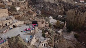 A historic stone courtyard with outdoor seating and a mosque. - Karamanli Konagi (Guzelyurt)