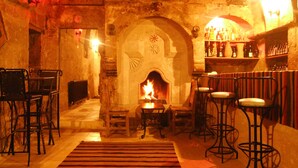 Un interior acogedor con chimenea de piedra, mesas de madera y taburetes de bar.