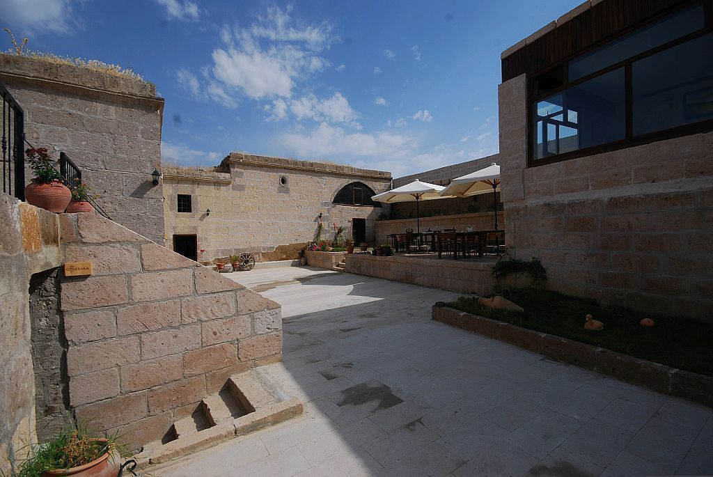 A courtyard with stone walls, outdoor seating, and potted plants.