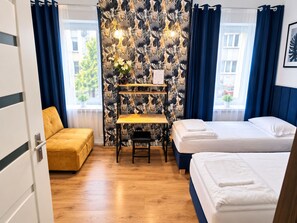 A hotel room with a bed, a desk, and a chair. There is a window with curtains. - ApartHostel Helvetia (Warsaw)