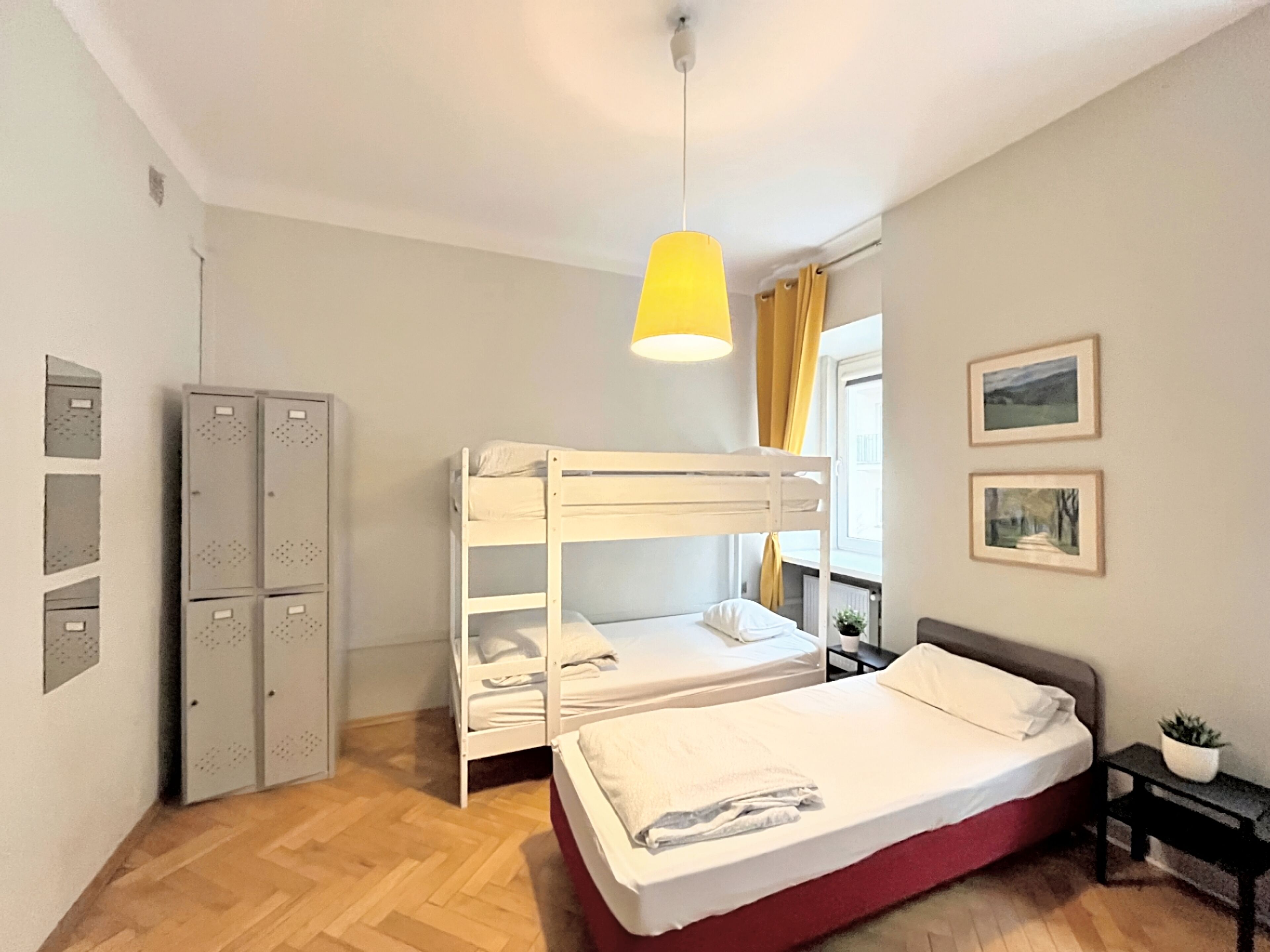 A room with bunk beds, a desk, a chair, a potted plant, and lockers.