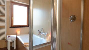A modern bathroom with a glass-enclosed shower, a vanity with a mirror, and a window providing natural light.
