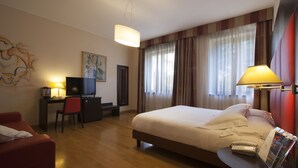 Una habitación de hotel con cama, escritorio, silla y televisión.