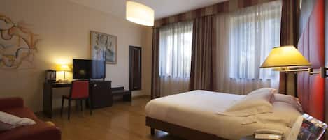 A hotel room with a bed, desk, chair, and a television.